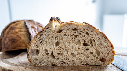 Cross-section of a wheat sourdough loaf with a light, open crumb on a wooden board
